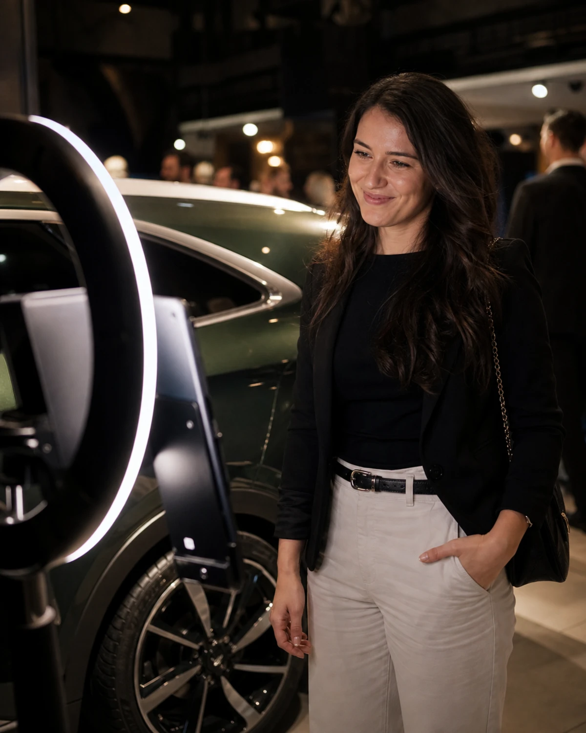 A launch-party guest poses at a ring-lit photo-booth station beside the deep-green flank of a newly launched car.