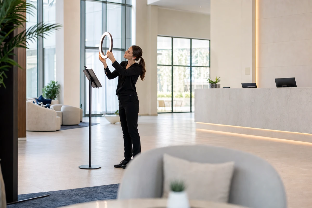 A hotel venue manager adjusts the ring light on a photo-booth station in an empty lobby in the morning.