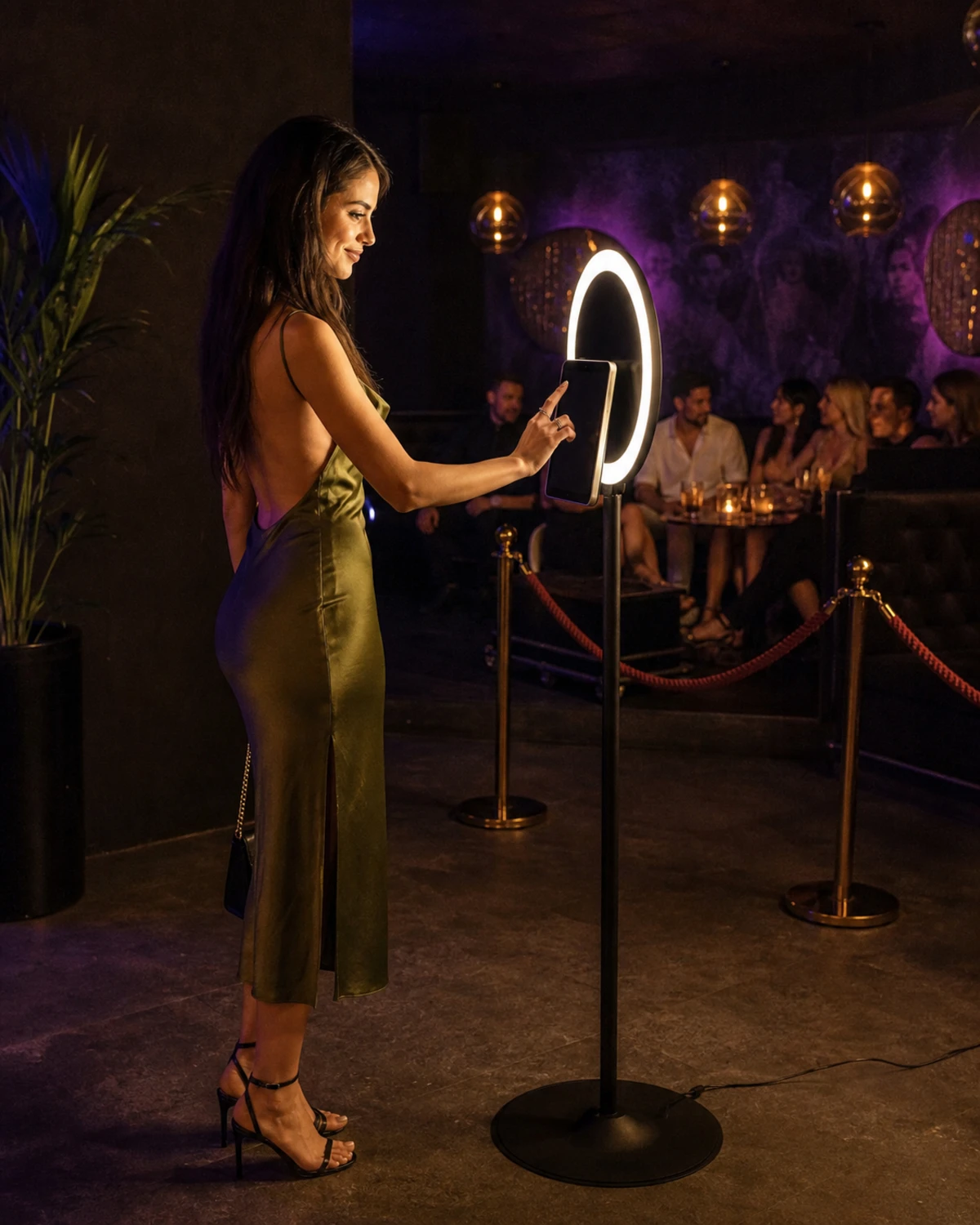 A nightclub guest interacts with an iPad photo-booth station set up at the edge of a VIP lounge, its screen angled away from the camera.