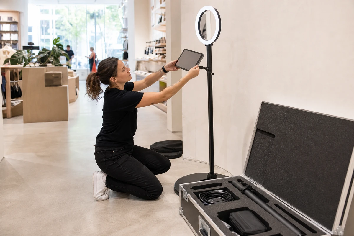 An operator assembles a photo booth kit from an open equipment case on a bright retail floor