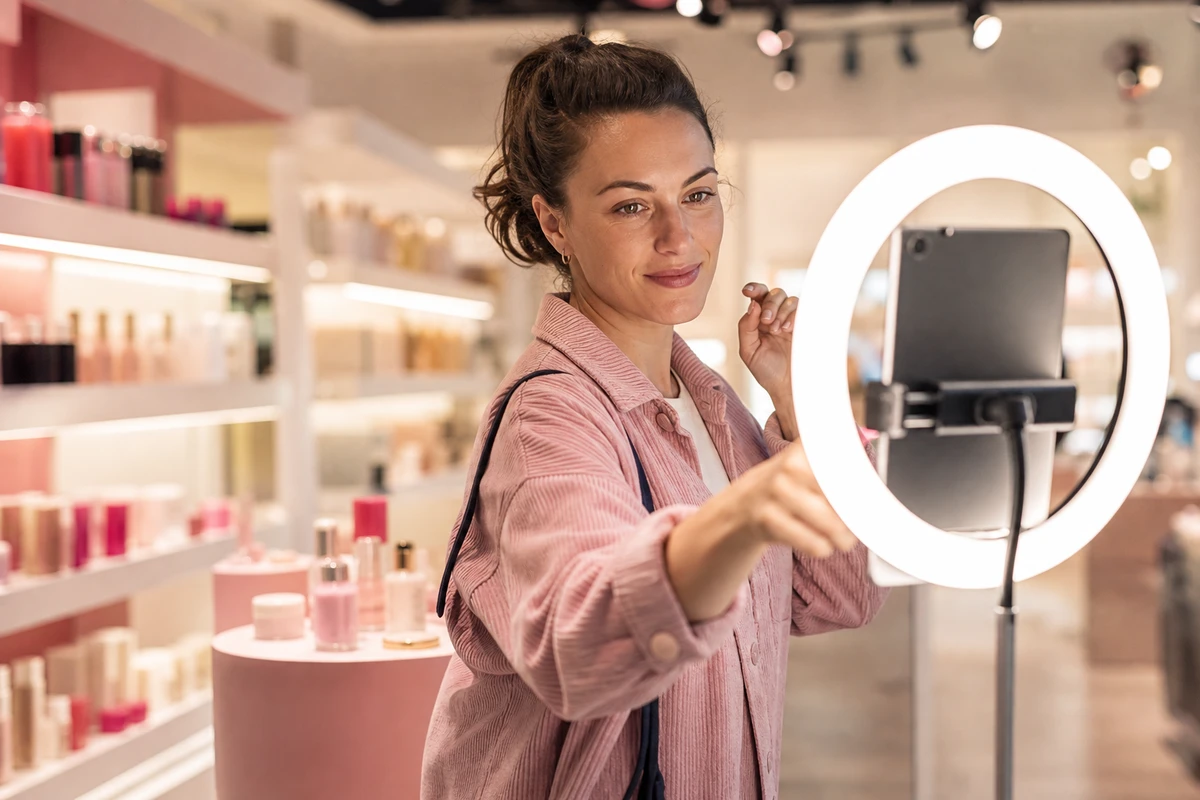 A shopper taking her own photo at an interactive photo installation on a beauty retail floor.