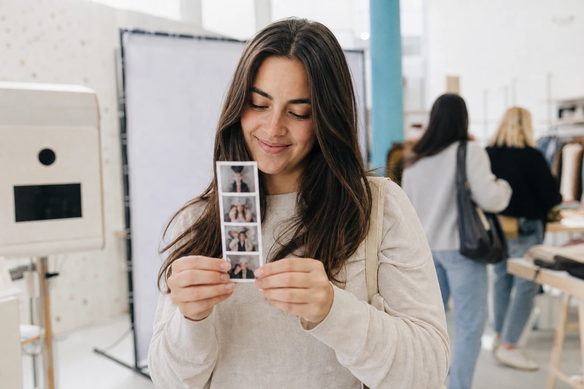 A shopper at a retail pop-up holding up a freshly printed photo strip she received at the event.