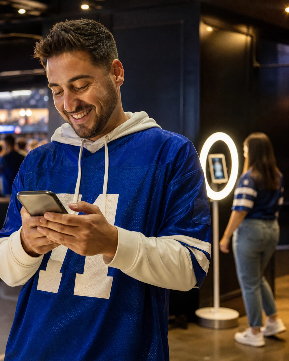 A sports fan checking their phone for a just-delivered photo after using a stadium photo booth.