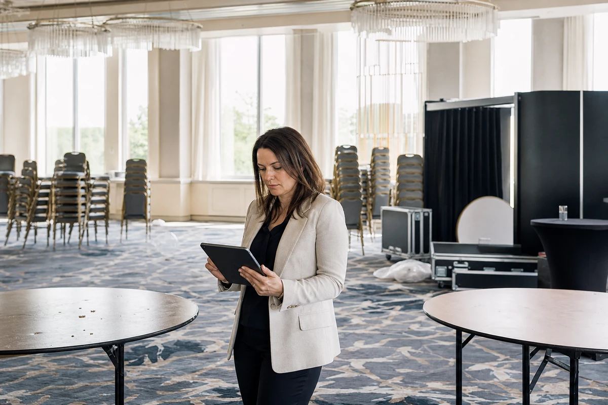 A venue manager reviews the night on a tablet in an emptied gala ballroom the morning after the event.